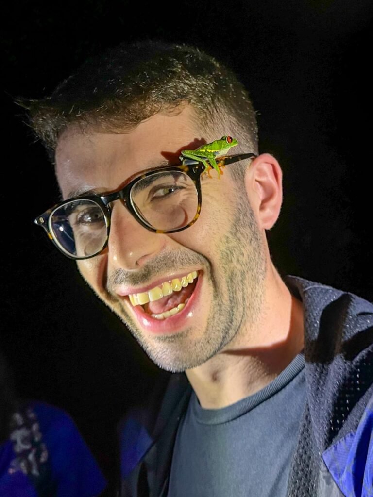 Tourist enjoying a night walk in Tortuguero with a red-eyed tree frog on his glasses.