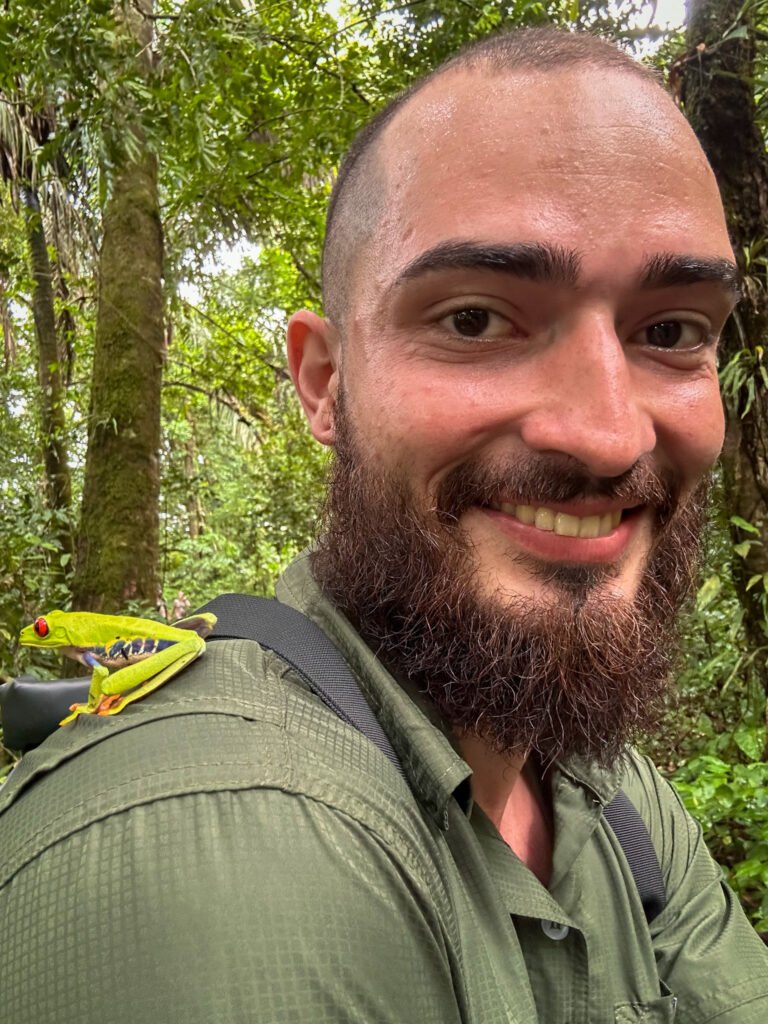 Boa, the naturalist guide, with a vibrant green frog on his shoulder in Tortuguero’s rainforest.