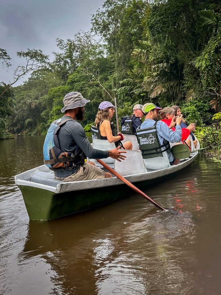 Wildlife tour guide leading a small-group canoe tour in Tortuguero National Park, Costa Rica, through lush rainforest waterways.