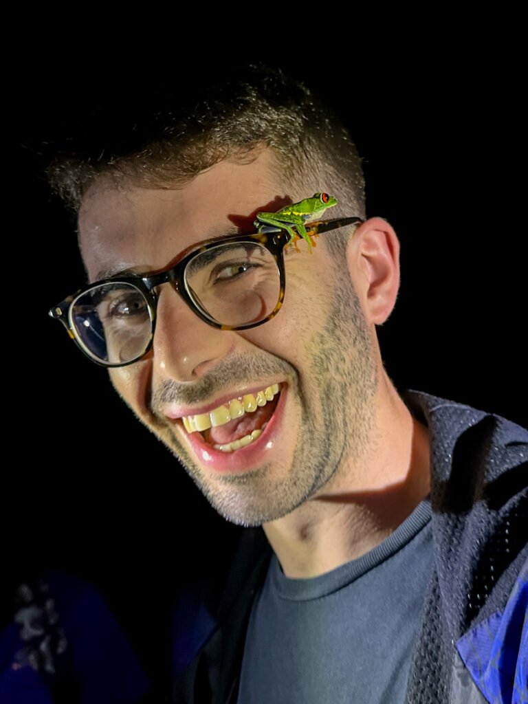 Happy tourist with a small frog sitting on their glasses during a night walk in Tortuguero.